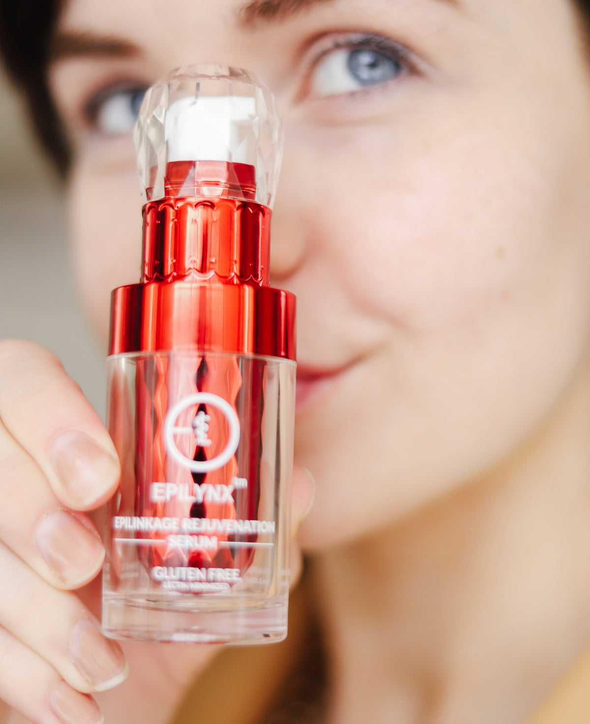 Woman holding the red serum bottle up to her face