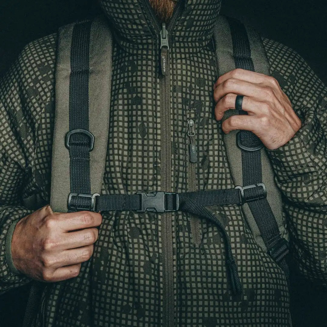Person adjusting the chest strap across the shoulder straps of the olive green Recycled Firefighter 24 Hour Backpack