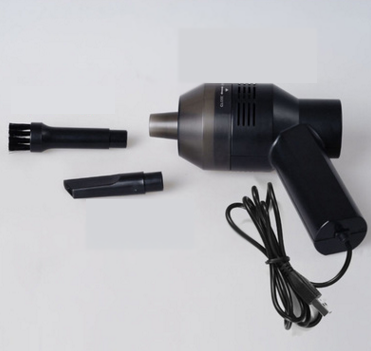 Black mini vacuum cleaner beside a brush attachment and a coiled cable