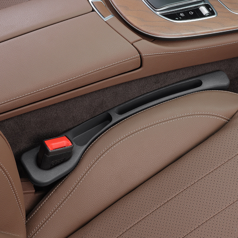 Black CHICAMOR SeatSlot car seat gap filler installed between a brown leather car seat and the centre console