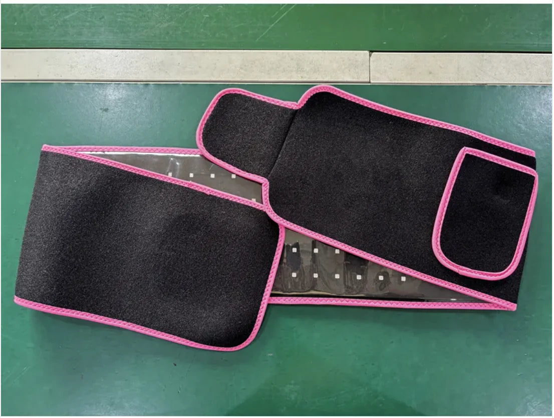 ReviveFlex red light therapy belt in black with pink edging, laid flat on a green mat