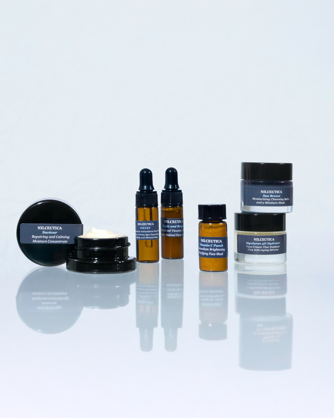 Line-up of NILCEUTICA dark jars and small amber bottles on a reflective white surface
