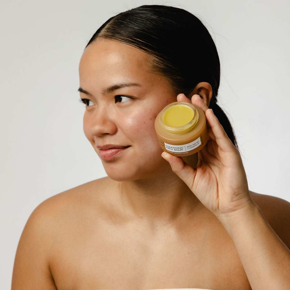 Woman holding an UpCircle balm jar against her cheek
