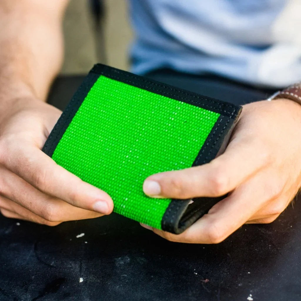 Hands holding a bright green fire hose wallet over dark clothing