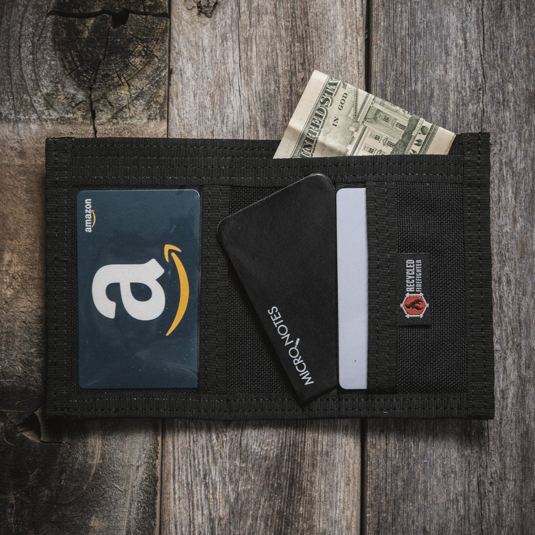 Open black wallet on wooden planks holding an Amazon gift card, cash and a card