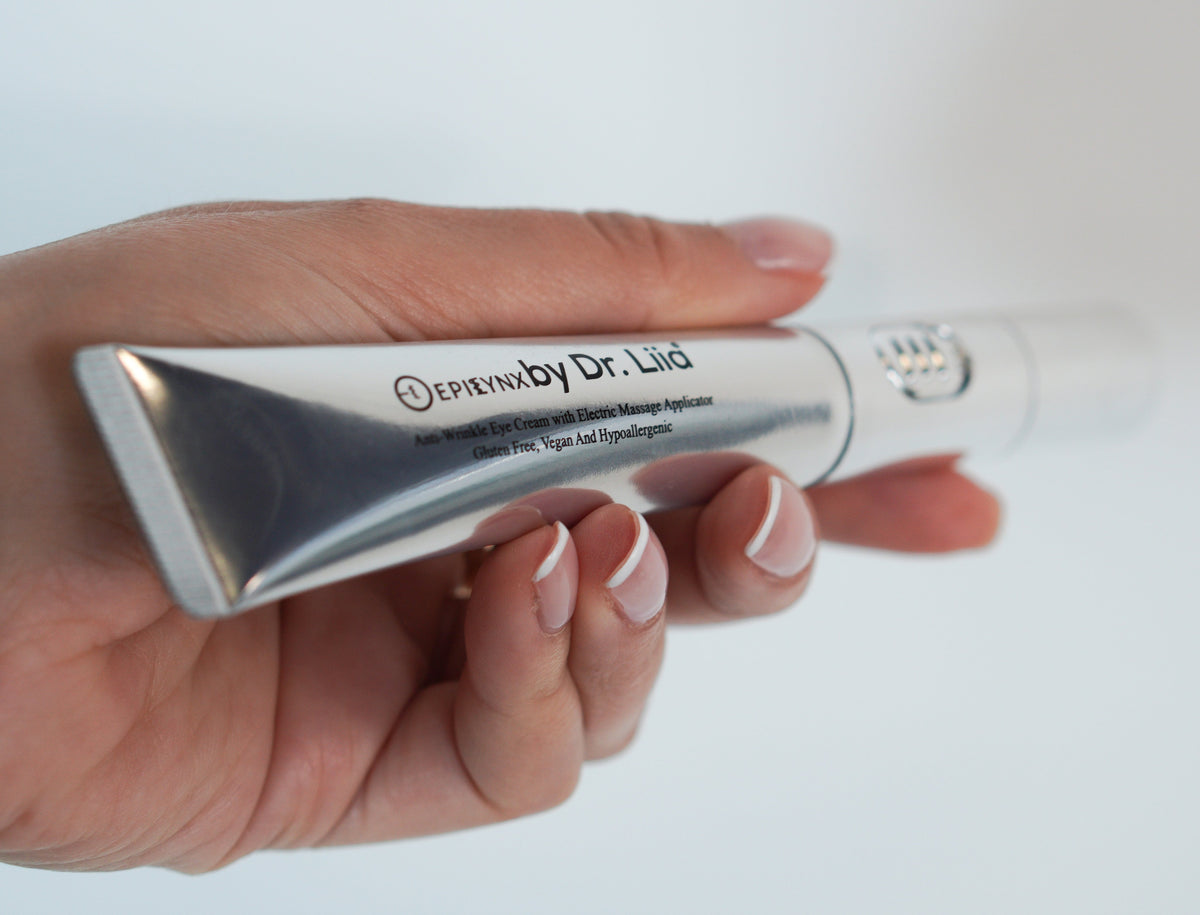 Hand holding the silver eye cream tube from the side