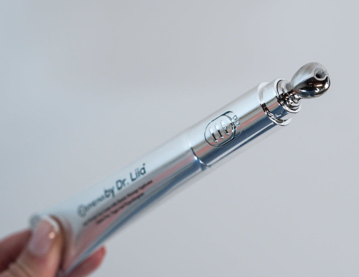 Hand holding the silver eye cream tube against a light background