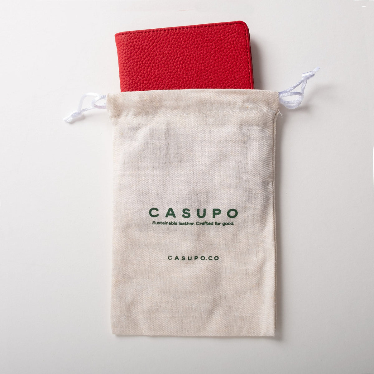 Red passport wallet partly inside a cream CASUPO drawstring pouch