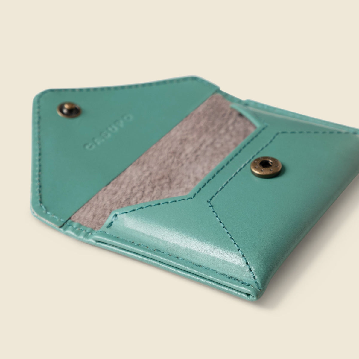 CASUPO teal mini envelope wallet at an angle with the flap open, showing a gray lining and metal snap