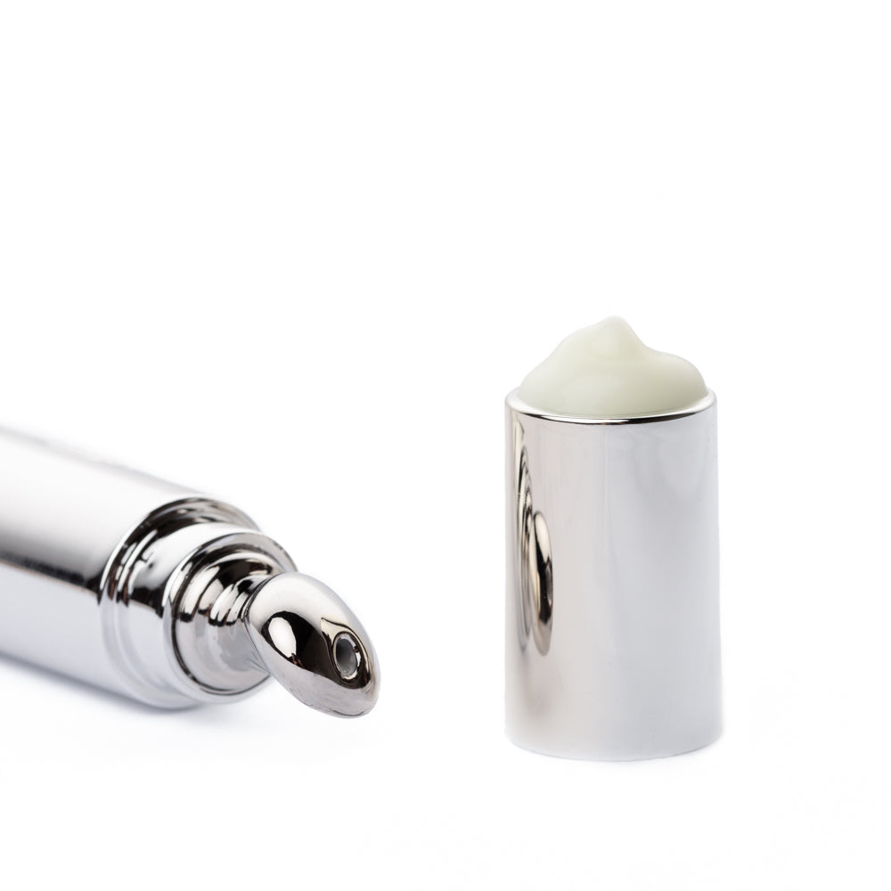 Eye cream tube beside its open cap filled with cream