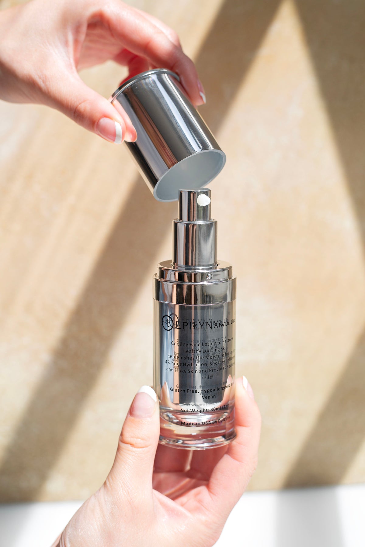 Hands holding the EpiLynx moisturizer bottle with the cap lifted off