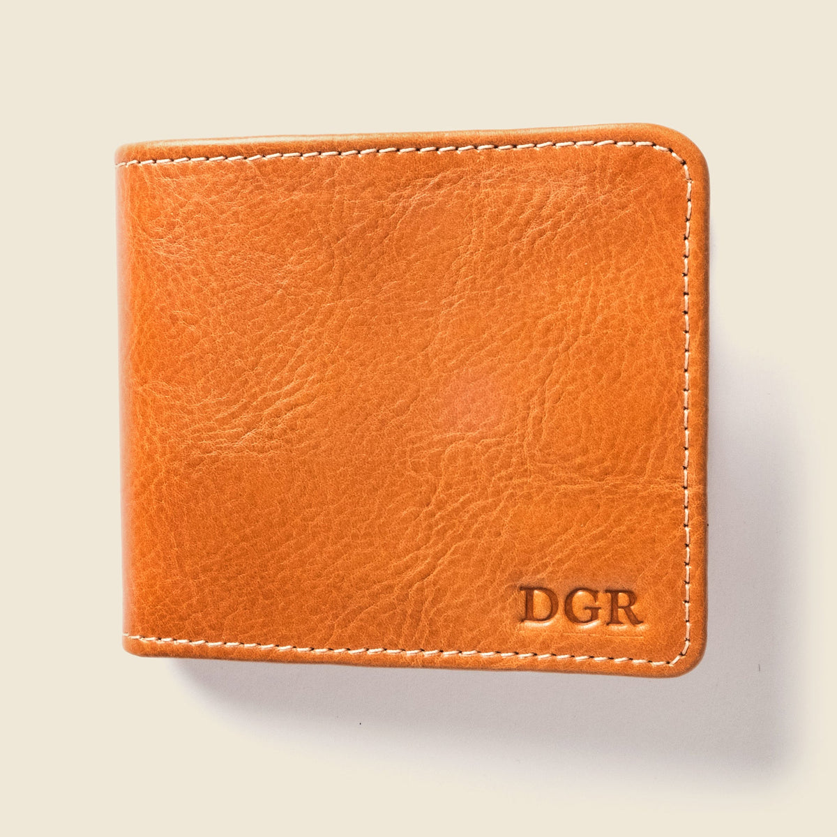 Closed tan leather billfold with the initials DGR stamped in the lower corner
