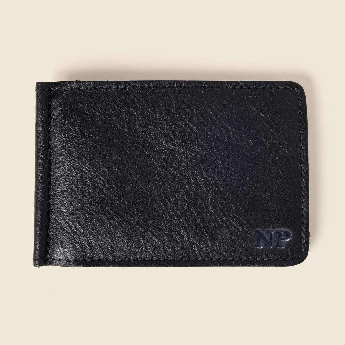 Black leather money clip wallet, front view, with a small monogram in the lower corner