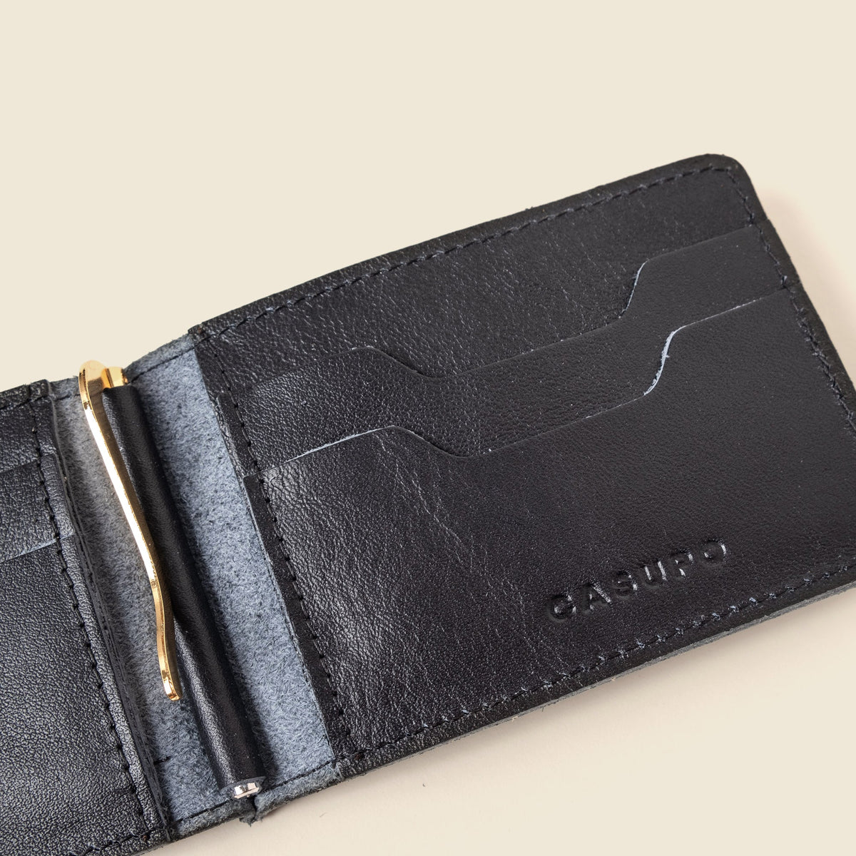 Interior of the black leather wallet at an angle showing the gold clip and empty card pockets