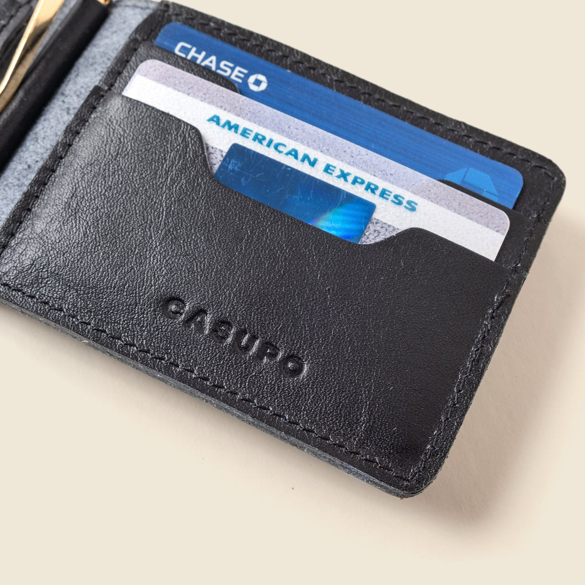 Close-up of cards in the front slot of the black leather wallet above the CASUPO logo