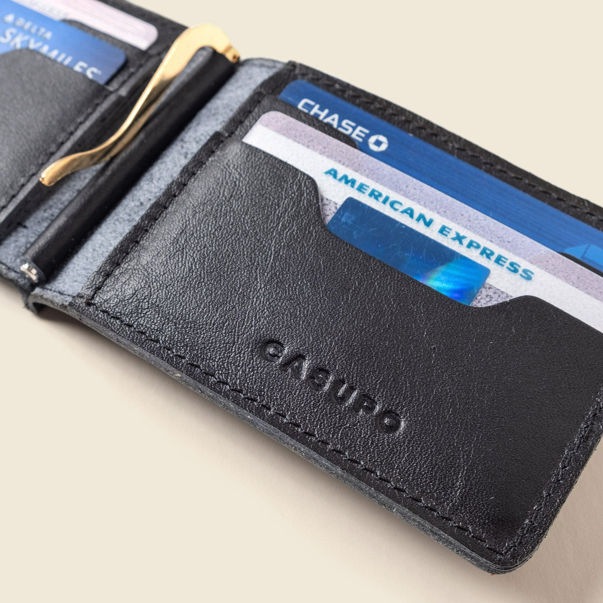 Close-up of the black leather wallet's card slot holding cards beside a gold money clip