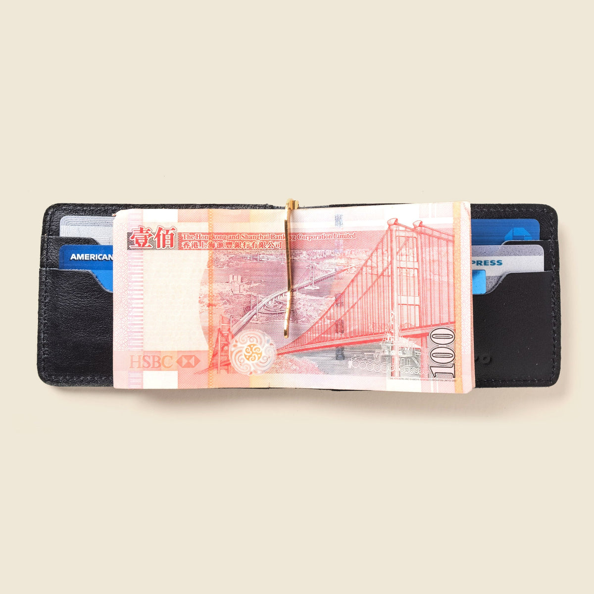 Open black leather wallet with a banknote held in the gold money clip and cards in the slots