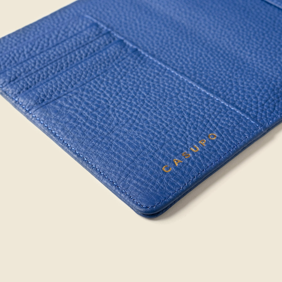 Close-up of the cobalt blue passport wallet's card slots and gold CASUPO logo