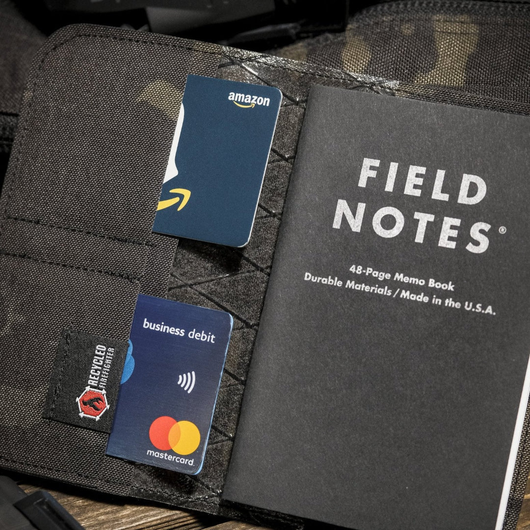 Close-up of the open black multicam Field Notes Wallet holding a notebook and two cards