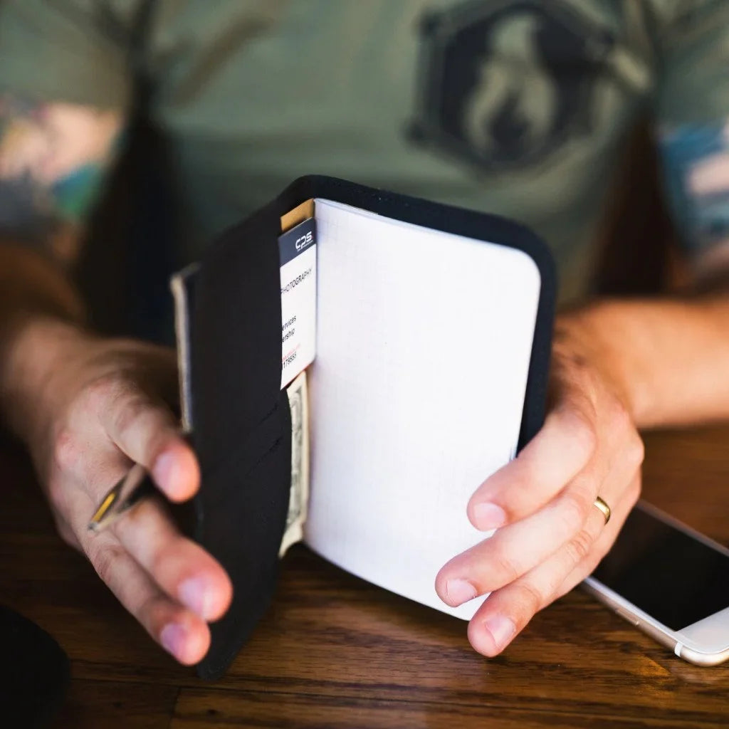 Man in a green T-shirt holding the open black Field Notes Wallet with a notebook page
