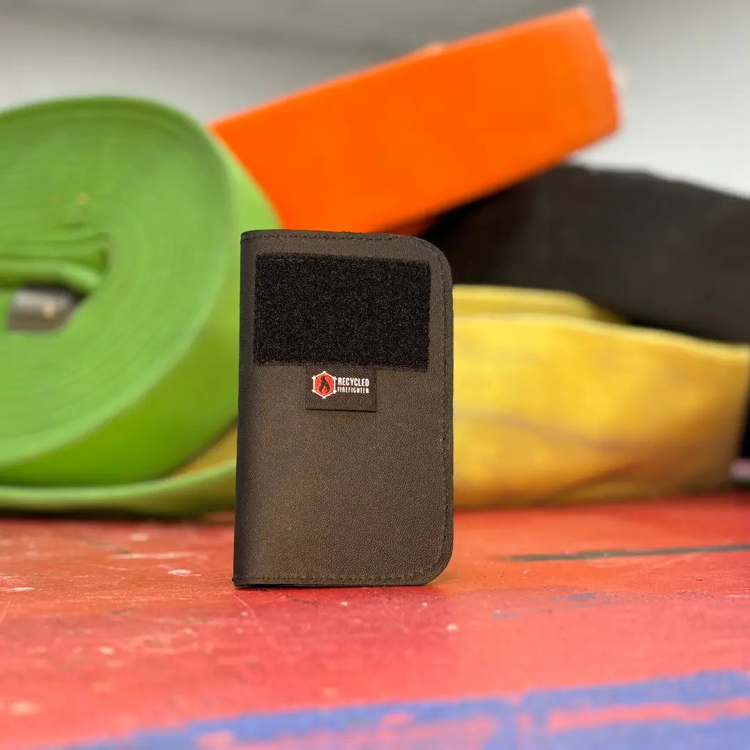 Small olive Field Notes Wallet with a patch panel standing on a red wooden surface