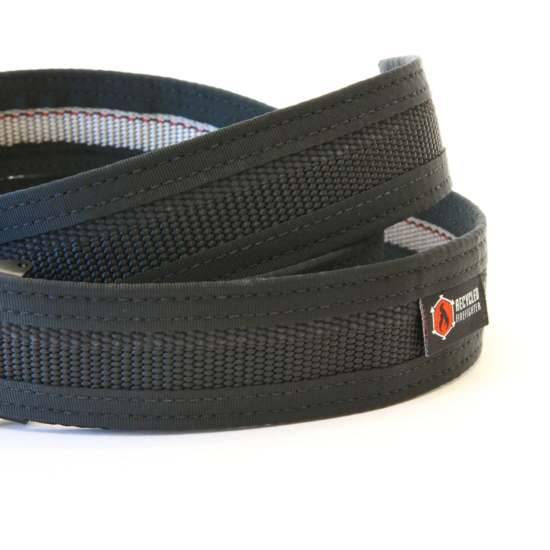 Recycled Firefighter Fire Hose EDC Belt in black, coiled to show its woven texture and logo patch