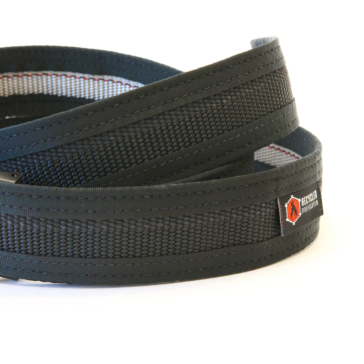 Recycled Firefighter Fire Hose EDC Belt in black, coiled to show its woven texture and logo patch