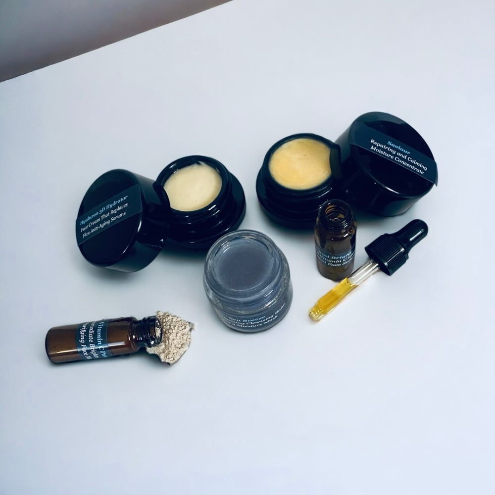 Open jars of cream and balm with a dropper bottle and small vials on a white table