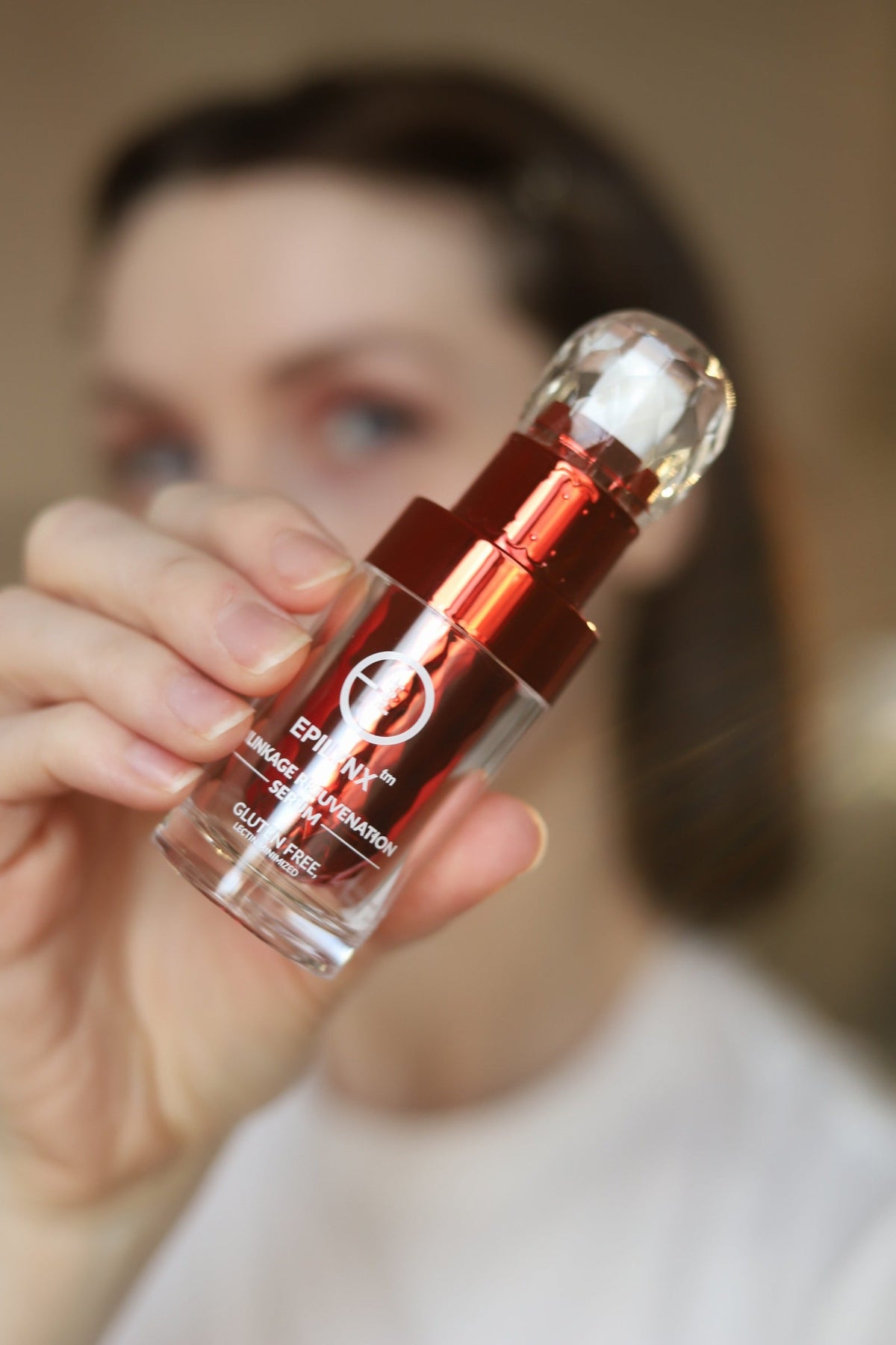 Woman holding a red serum bottle close to the camera