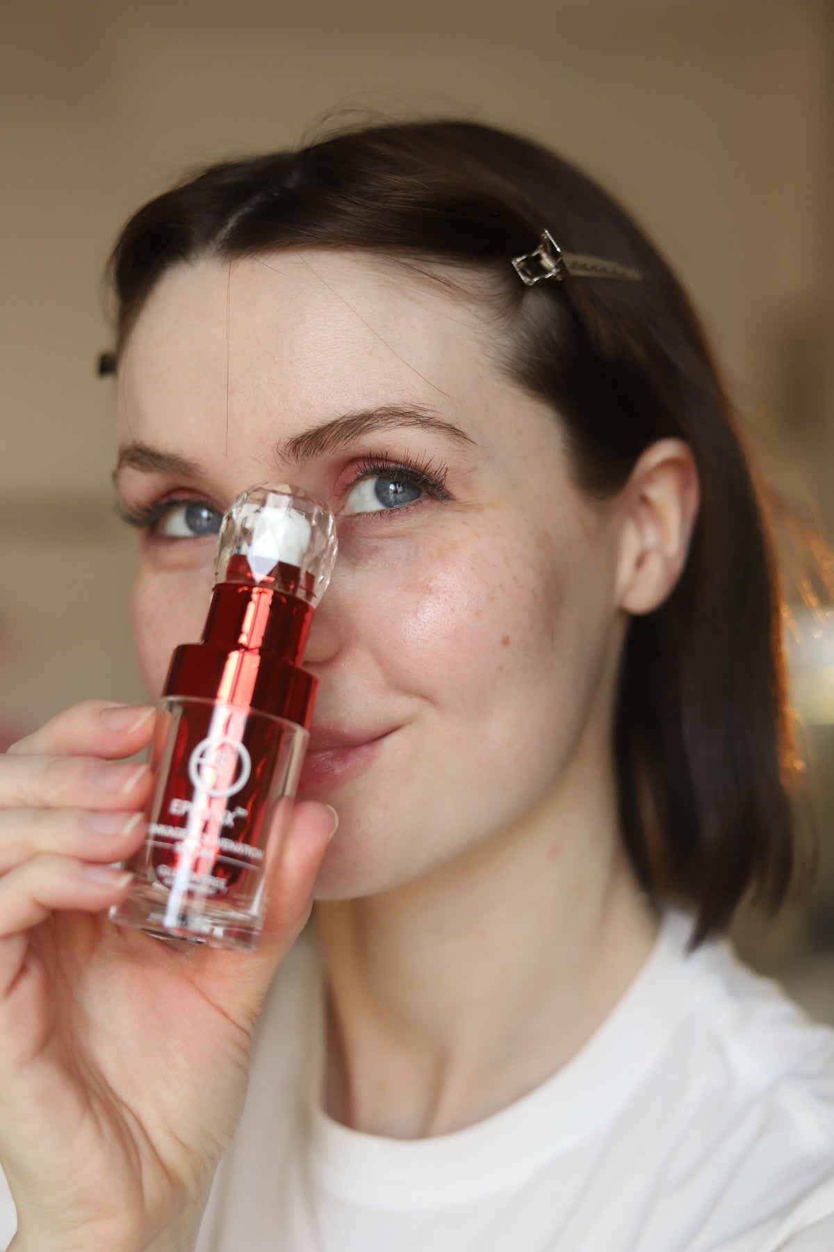 Woman holding the red serum bottle to her nose