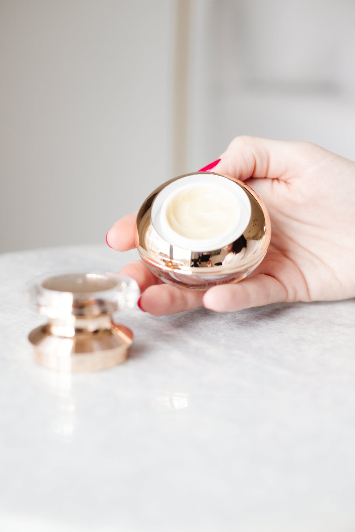 Hand holding the gold EpiLynx eye cream jar above a marble table