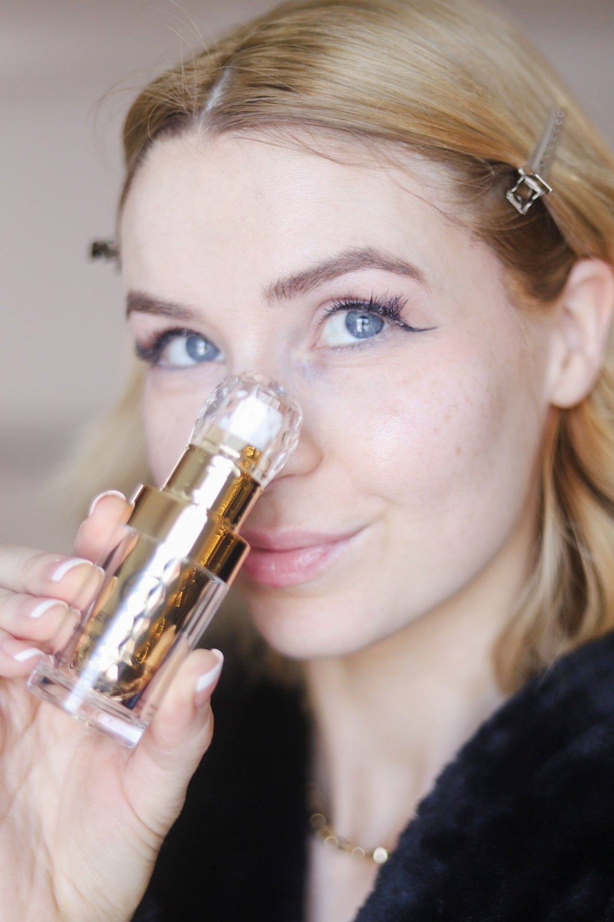 Woman holding the gold serum bottle to her nose
