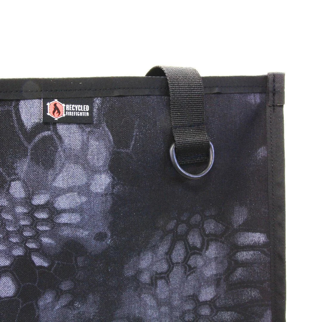 Close-up of the Tactical Tote's handle attachment with a metal D-ring, logo patch and scale-pattern fabric
