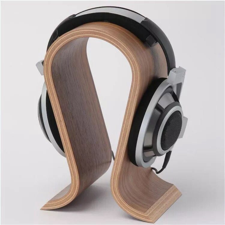 Over-ear headphones resting on a walnut-look curved wooden stand