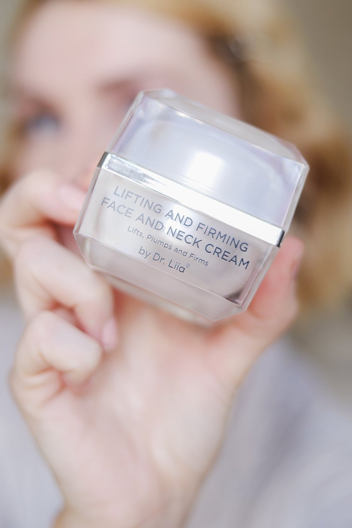 Hand holding the cream jar toward the camera
