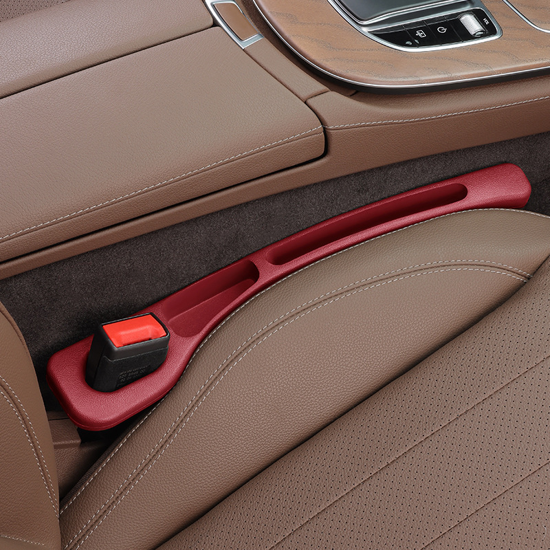 Red CHICAMOR SeatSlot car seat gap filler installed between a brown leather car seat and the centre console