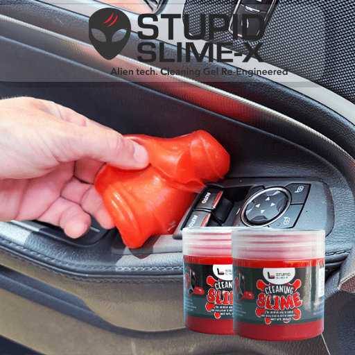 Hand pressing red cleaning gel into a car air vent, with two jars of the gel below