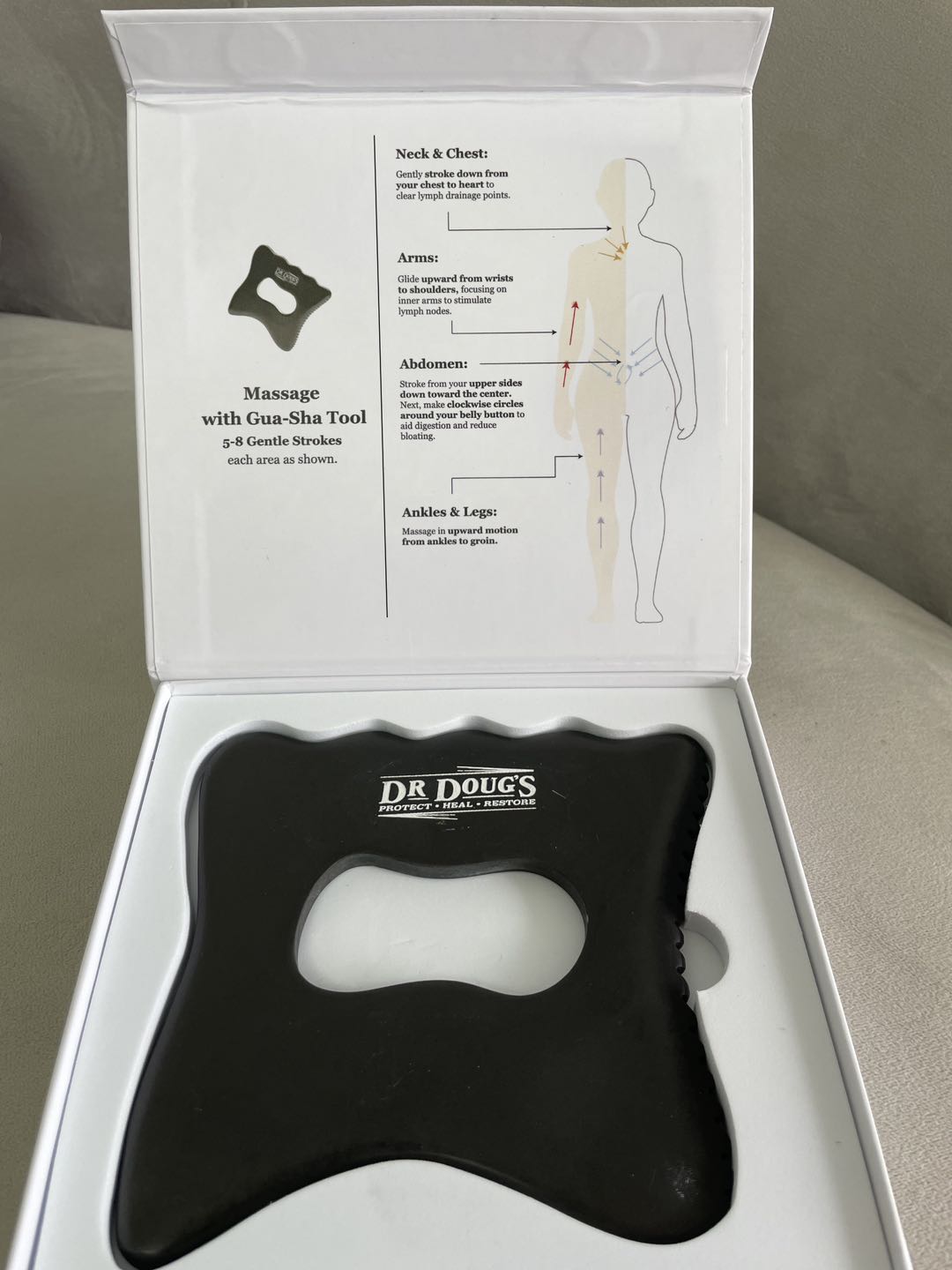 Large black gua sha tool in an open white box with an instruction card
